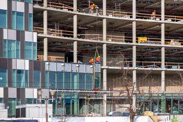 New residential and office block buildings being constructed. Industrial building site. Workers putting windows in under construction skyscraper. 