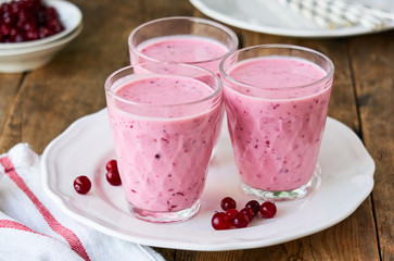 Yogurt smoothies with fresh cranberries on a wooden background