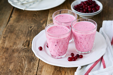 Yogurt smoothies with fresh cranberries on a wooden background