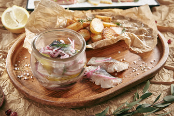 Marinated Herring in Vinegar with Potatoes, Oil, Dill, Onion and Spices on Rustic Background