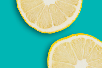 Two round pieces of fresh ripe sliced lemons on green table on cuisine. Copy space for your text. Top view. Cooking concept
