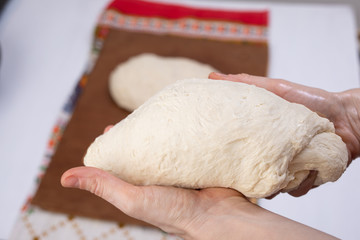 Hands kneading a bread pie dough close up on. Women to mold the dough. A dough will rise before baking in oven