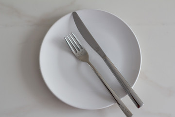 white plate, fork and knife on white background.