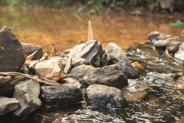 close up of stone that use to make weir in river with water steam flowing