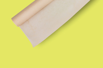 One roll of brown baker paper on yellow table on cuisine with copy space for your text. Top view. Flat lay. Cooking concept