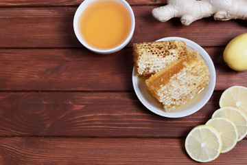 Traditional medicine. Honey and bee honeycombs. Ginger and lemon on the wooden table. Place for text. Top view.