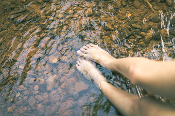 in the memory, woman put feet in water, have stone under river with reflection