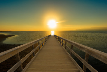 A walkway towards the sea in a sunset
