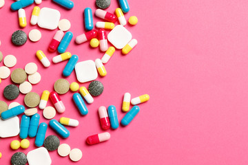 Multi-colored vitamins on a pink background. Place for text. Top view.