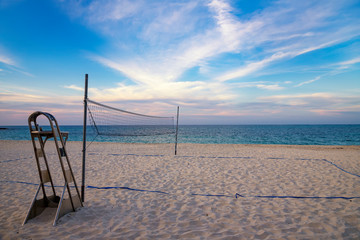 A beach volleyball net on the sandy tropical beach at the sunset / sunrise