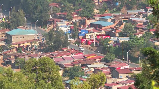 View of small, closely packed houses on a hillside of a semi-rural suburb of Kigali, Car trafic in a road. Rwanda
