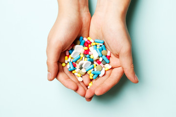 Multi-colored vitamins in the hands on a blue background. Place for text. Top view.