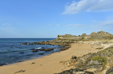 Fototapeta na wymiar Castro de Barona, Galicia, Spain. Prehistoric settlement ruins and beach with rocks. Blue sea, sunny day.
