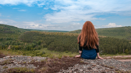 Fototapeta premium A beautiful girl with red hair enjoys great view of ukrainian forest