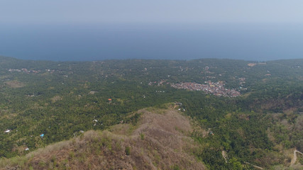 Naklejka premium tropical landscape sea coast with towns, mountain slopes covered with vegetation. Aerial view village by sea Indonesia.
