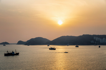 The setting sun on the sea, ships, mountains, a beautiful evening landscape