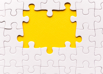 Copy space of unfinished white jigsaw puzzle pieces. One missing jigsaw piece on yellow background - obrazy, fototapety, plakaty