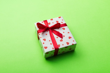 Valentine or other holiday handmade present in paper with red hearts and gifts box in holiday wrapper. Present box of gift on green colored table top view with copy space, empty space for design