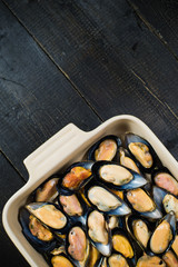 Fresh mussels in shells. Black wooden background, top view.