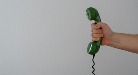 hand holding green telephone receiver with copy space, banner size
