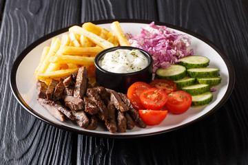 Freshly cooked shawarma plate with beef, french fries, vegetables and sauce close-up. horizontal