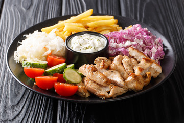 Doner kebab on a plate with french fries, salad and sauce close-up on a table. horizontal