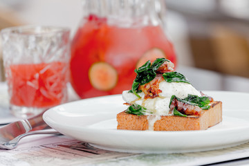 Eggs benedict with brioche, bacon and spinach.