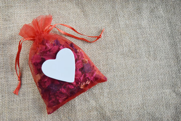 Background brown sack bag with a white heart on a red dried flower bag. Concept the day of love Valentine and empty space for text.