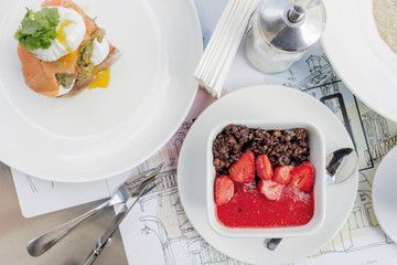 Breakfast table: toast with guacamole, salmon and poached egg and granola with chocolate and strawberry.