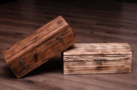 Two closed wooden luxury gift boxes or caskets on wood background.