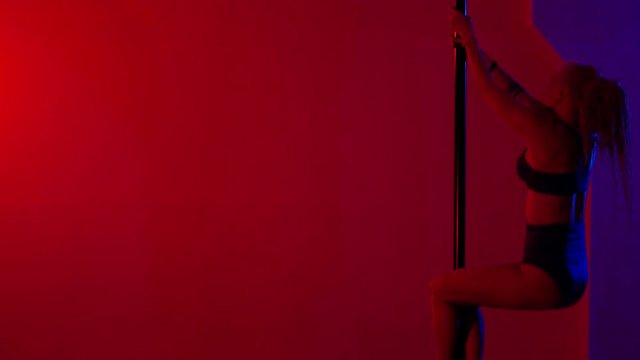 Adult sexy woman dancing dance in an intimate setting. Silhouette of a sexy woman dancing on red background. Pole dance from an old woman