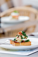 Eggs benedict with brioche, bacon and spinach.