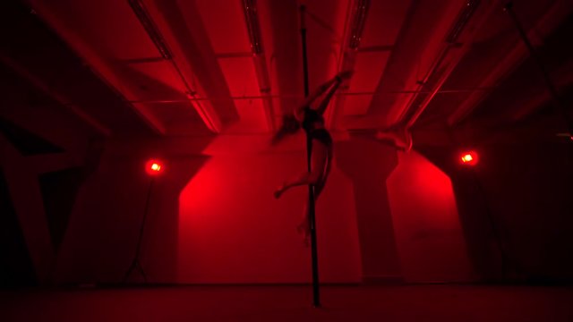 Adult sexy woman dancing dance in an intimate setting. Silhouette of a sexy woman dancing on red background. Pole dance from an old woman