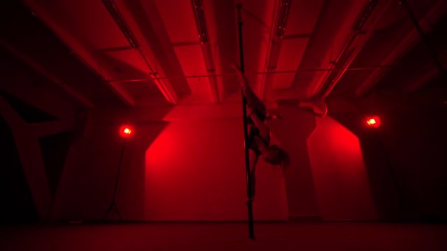 Adult sexy woman dancing dance in an intimate setting. Silhouette of a sexy woman dancing on red background. Pole dance from an old woman