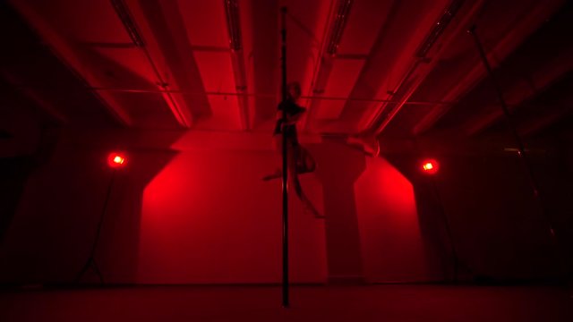 Adult sexy woman dancing dance in an intimate setting. Silhouette of a sexy woman dancing on red background. Pole dance from an old woman
