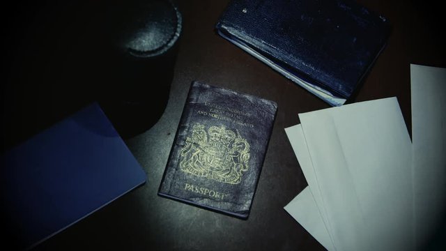Gloved thief with flashlight steals a British passport from a pile of documents