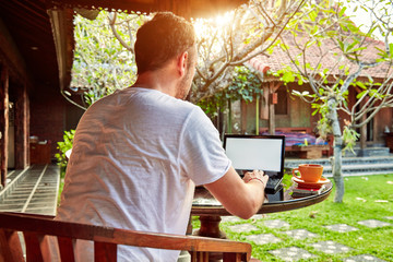 Man with coffee / tea and laptop on a home porch.