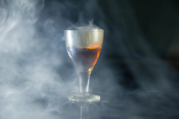 glass of cognac in the smoke on a black background