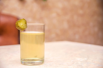 A glass of pickle with a piece of cucumber on the table. Traditional Russian hangover cure