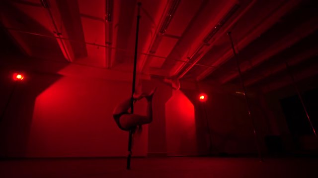 Adult sexy woman dancing dance in an intimate setting. Silhouette of a sexy woman dancing on red background. Pole dance from an old woman