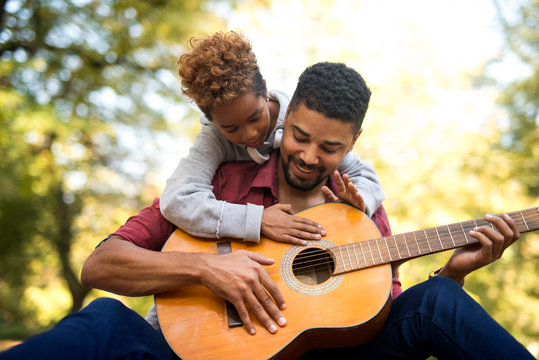 Father and daughter playing guitar together. Happy family having wonderful time together.