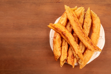 An overhead photo of traditional Spanish porras, a typical Madrid Sunday breakfast, on a dark rustic wooden table with a place for text