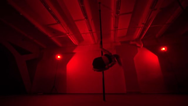 Adult sexy woman dancing dance in an intimate setting. Silhouette of a sexy woman dancing on red background. Pole dance from an old woman
