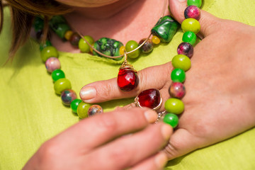 Woman wearing beautiful gemstone necklace and golden ring with amber. Jewelry made of coral, olivine and agate stones. Powerful energy of healing crystals