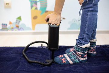 Woman with hand air pump inflatable mattress or inflatable bed at home. Body part, selective focus