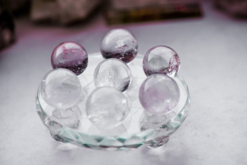 Macro shot of transparent crystal balls with colorful ornaments and sun reflections in it, on turquoise glass pad. Fortune telling. Love, money, luck, success.