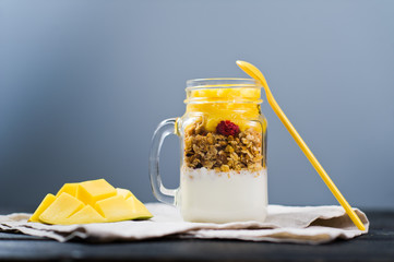Healthy breakfast muesli and yogurt with mango smoothie in glass mason jars, white background