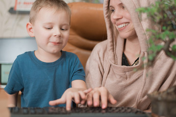 Mother and little son are sitting at the computer.