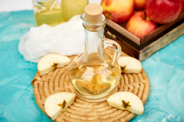 Glass Bottle of apple organic vinegar on blue background.