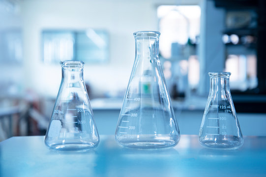 three size of glass flasks in blue education chemistry science laboratory background